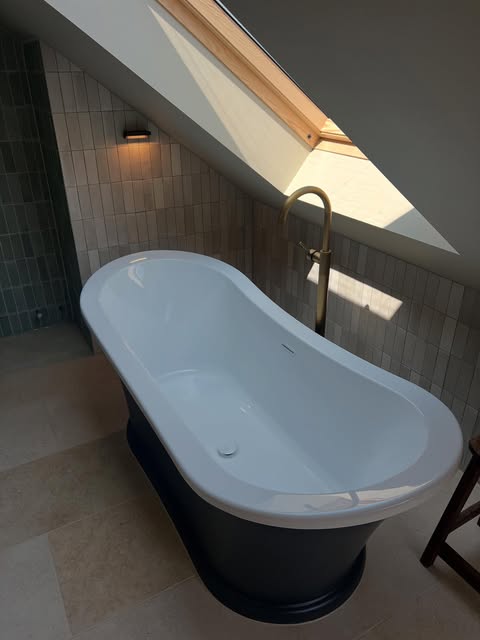 Warm wall lighting beside a freestanding bath